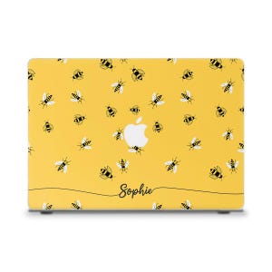 Puede incluir: Funda amarilla para portátil con un patrón de abejas negras y amarillas con alas blancas. El logotipo de Apple es visible. El nombre "Sophie" está escrito en cursiva. La funda está diseñada para un portátil.