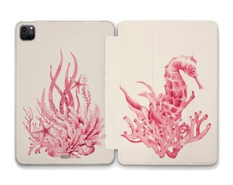 Può includere: Una custodia per telefono rosa e bianca con un'illustrazione ad acquerello di un cavalluccio marino e coralli. Il cavalluccio marino è sul lato destro della custodia e il corallo sul lato sinistro.