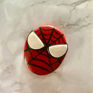 May include: A red and black Spider-Man face cookie with white eyes.