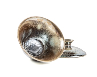 May include: Two ceramic bowls with a dark brown and silver glaze. The bowls are stacked on top of each other.