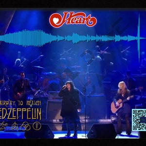Könnte beinhalten: Ein Live-Auftritt der Band Heart, die "Stairway to Heaven" von Led Zeppelin singen. Die Band steht auf der Bühne mit einem kompletten Orchester hinter sich. Die Bühne ist mit blauen Lichtern beleuchtet. Der Name der Band, "Heart", ist oben im Bild in einem roten Herzlogo dargestellt. Der Titel des Songs und der Name der Band sind unten im Bild in goldenen Buchstaben dargestellt.