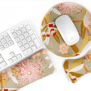 Puede incluir: Un teclado blanco, un ratón de ordenador blanco y un reposamuñecas, todos con un patrón floral en tonos de rosa, naranja y marrón. El patrón floral está sobre un fondo beige.