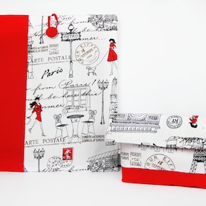 May include: Two fabric pouches with a red trim and a white background featuring a Parisian theme. The pouches have black and white illustrations of the Eiffel Tower, street lamps, and a woman in a red dress. The text "Paris" and "ARTE POSTALE" are visible on the pouches.