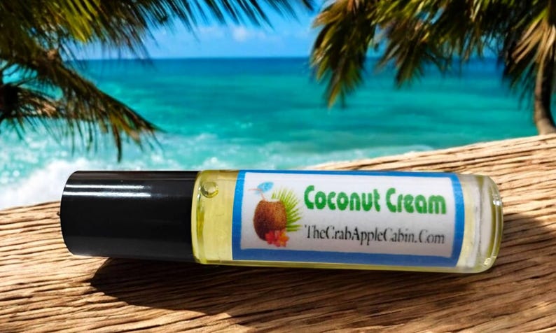 May include: A small, clear glass roller bottle with a black cap. The label is blue and white with the text "Coconut Cream" and "TheCrabAppleCabin.com".