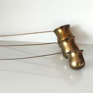 Op de afbeelding: Drie Turkse koffiepotten van messing met lange handvatten. De potten zijn in elkaar genest, met de kleinste pot onderaan en de grootste bovenaan.