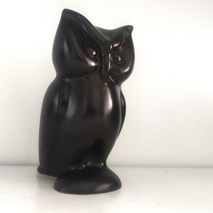 May include: A black ceramic owl figurine with a glossy finish. The owl is perched with its head tilted to the side, looking to the right.