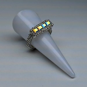 Könnte beinhalten: Ein silberner Ring mit einer Reihe von regenbogenfarbenen quadratischen Kristallen.