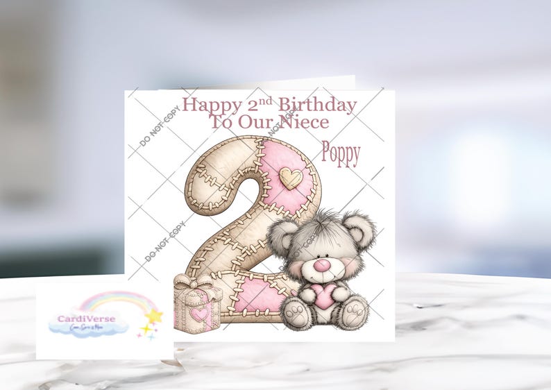 Może przedstawiać: Kwadratowa kartka okolicznościowa z napisem Happy 2nd Birthday To Our Niece Poppy. Projekt zawiera dużą cyfrę dwa z przeszywanym wzorem patchworkowym w kolorze beżowym i r&oacute;żowym, małe pudełko prezentowe oraz puszystego szarego misia z r&oacute;żowym sercem.