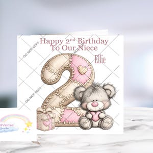 Może przedstawiać: Kwadratowa kartka okolicznościowa z napisem Happy 2nd Birthday To Our Niece Ellie. Projekt zawiera dużą beżowo-r&oacute;żową cyfrę dwa z efektem przeszycia, małe pudełko prezentowe oraz szarego pluszowego misia trzymającego r&oacute;żowe serce na białym tle.
