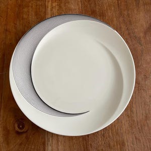 May include: White ceramic dinner plate with a black abstract design of curved lines.