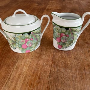 Peut inclure: Un ensemble sucrier et crémier en porcelaine blanche avec un motif de vigne verte. Le sucrier a un couvercle et une anse. Le crémier a une anse.