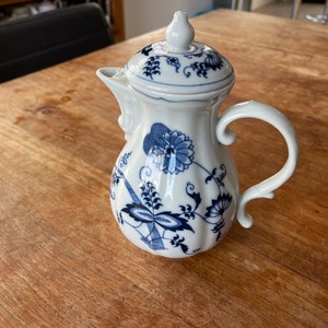以下が含まれることがあります： 青と白の花柄の白い磁器製のクリーマー。クリーマーには蓋と取っ手があります。
