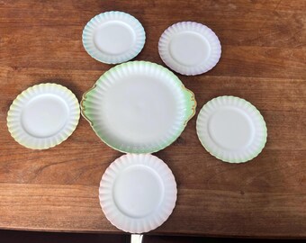Puede incluir: Un conjunto de platos y platillos de estilo vintage. El juego incluye una fuente grande con ribete verde y dorado, y platos más pequeños con bordes festoneados en colores pastel en tonos azules, amarillos y rosas.