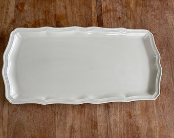 May include: A white rectangular serving platter with a scalloped edge.
