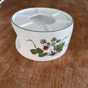 Pode incluir: Aquecedor de chá de cerâmica branca com uma borda verde e um design floral de morangos e folhas.