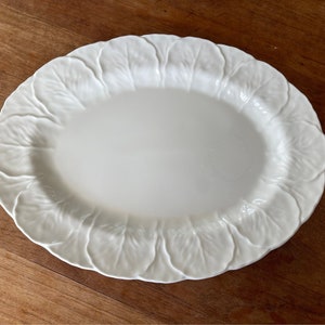 Op de afbeelding: Witte ovale serveerschaal met een decoratief ontwerp van koolbladeren.