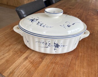 May include: White ceramic casserole dish with a blue floral design and a matching lid. The dish has a fluted edge and a blue trim around the rim.