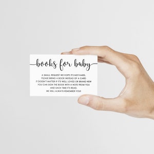 May include: A white card with the text "books for baby" in elegant script. The card also includes a request for guests to bring a book instead of a card for the baby. The card is held by a hand.
