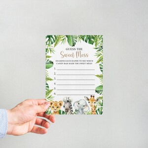 May include: A printable baby shower game card with a jungle theme. The card has a green leafy background with a gold title that says "Guess the Sweet Mess". The card has instructions to examine each diaper to see which candy bar made the sweet mess. There are six lines for guests to write their guesses.