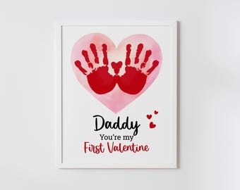 May include: A pink watercolor heart with red handprints inside. The text "Daddy You're my First Valentine" is below the heart.