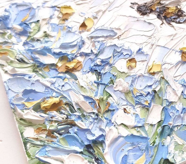 May include: A close-up of a painting depicting a cluster of blue and white flowers with yellow centers. The flowers are painted in a thick, textured style, giving the impression of brushstrokes.