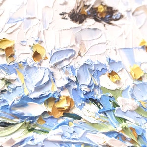 May include: A close-up of an oil painting depicting a field of blue and white flowers with yellow centers. The flowers are painted with thick, textured strokes of paint, giving the painting a three-dimensional effect.