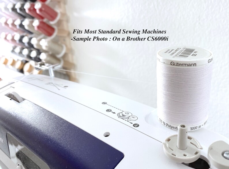 Pode incluir: Uma m&aacute;quina de costura branca com um carretel de linha de poli&eacute;ster branca G&uuml;termann colocado em cima. A m&aacute;quina apresenta diagramas de enfiamento impressos e o texto: Fits Most Standard Sewing Machines -Sample Photo : On a Brother CS6000i.