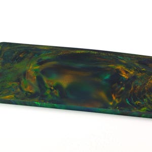 Op de afbeelding: Een rechthoekig blok met afgeronde hoeken met een wervelend patroon van diep bosgroen, donkerblauwgroen en metallic goudtinten. Het oppervlak heeft een gladde, gepolijste afwerking met een halfdoorschijnend uiterlijk dat diepte en beweging creëert.
