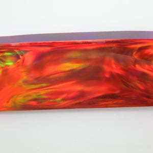 May include: A rectangular, iridescent object with a fiery red, orange, and yellow colour scheme. The object has a glossy finish and appears to be made of a translucent material. The edges are slightly rounded.