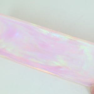 Op de afbeelding: Een rechthoekig, iriserend vel plastic met een roze en wit swirl-patroon.