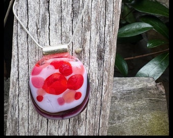 Glass fused pendant custom made by Jeanne. Colors are reds and numerous pinks. There are hints of sparkling dichroic glass.