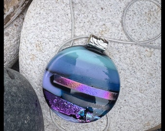 Bullseye glass pendant with a medley of light blues hints of lavander sparkle with purple dichroic accent and shimmering iridescent glass.