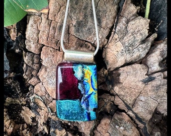 Hand made glass pendant. Fused by artists. Shimmering transparent deep red with layers of dichroic aqua and gold iridescent accents.