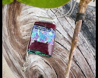 Hand made glass pendant. Fused by artist. Deep red and blacks with dichroic accent through the middle.