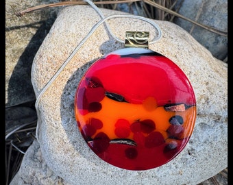 Round circle glass pendant bright red and orange with hints of  sparkling bronze and shimmering gold.