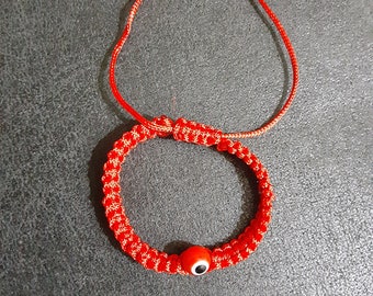May include: Red string bracelet with a blue evil eye charm. The bracelet has silver beads on each end.