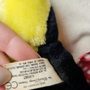 May include: A black and yellow plush toy with a white tag that reads "Made Exclusively For The Walt Disney Company Disney CE All New Materials Polyester Fibers HE ISIS: PA REGNO PA DISKR ORO PA 1378 MASS T-810 CARASA TRADING CORP SURBANK, CA, B.S PRODUCT OF KOREA PIR-100"
