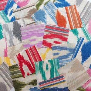 Può includere: Una collezione di campioni di tessuto in vari colori e motivi. I campioni presentano disegni a pennellate in blu, arancione, rosa e verde, oltre a motivi a righe e ikat. I campioni di tessuto sono disposti in modo sparso e sovrapposto.