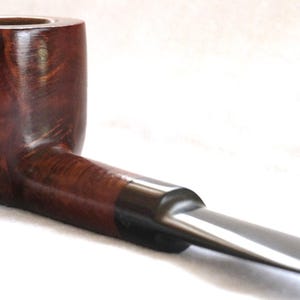 May include: A classic tobacco pipe with a curved stem and a dark brown, polished finish. The bowl is rounded, and the stem is a contrasting dark color. The pipe is designed for smoking and is set against a white background.