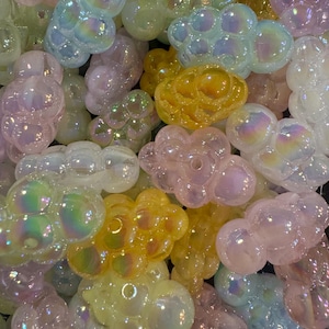 May include: A collection of iridescent glass bubble beads in various pastel colors, including pink, yellow, and blue. The beads are made of glass and have a smooth, rounded surface.