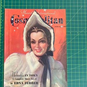 Pu&ograve; includere: Una copertina di rivista vintage con una donna che indossa un cappotto bianco con cappuccio bordato di pelliccia, con il titolo "Cosmopolitan" e il testo "Nobody's in Town, A Complete Short Novel by Edna Ferber" e "Special Christmas Issue".