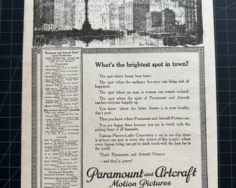 May include: A black and white newspaper clipping with a vintage illustration of a city skyline. The text reads "What's the brightest spot in town?" and "Paramount and Artcraft Motion Pictures".
