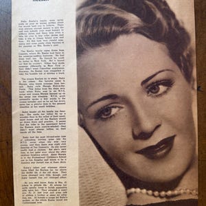 May include: A vintage black and white photograph of Ruby Keeler, a woman with dark hair styled in waves, wearing a pearl necklace. The image is from a printed page with text about her life and career.