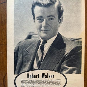 May include: Black and white vintage advertisement featuring Robert Walker. He is wearing a suit and tie. The advertisement includes text about Walker and his film career.