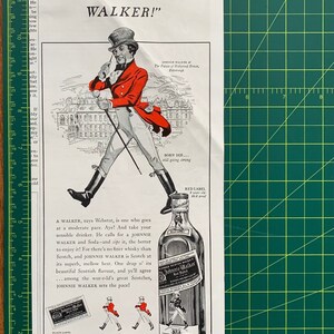 May include: A vintage advertisement for Johnnie Walker blended Scotch whisky. The ad features a man in a red hunting jacket and black riding boots walking with a stick. The text reads "Mind what your Webster has to say about a WALKER!" and "It's sensible to stick with Johnnie Walker Blended Scotch Whisky".