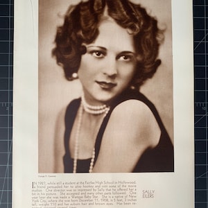 May include: Sepia-toned portrait of Sally Eilers, a Wampas Baby Star. She is wearing a pearl necklace and a dark dress. The image is from a vintage magazine, with text describing her early career.