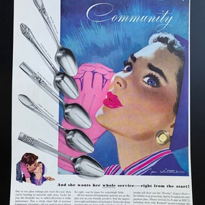 May include: A vintage advertisement for Community silverplate featuring a woman with blue eyes and red lips. The text reads "she's in love... and she loves Community" and "And she wants her whole service-right from the start!" The ad shows a variety of silver spoons with the names "White Orchid", "Evening Star", "Morning Star", "Lady Hamilton", and "Coronation" printed on them.
