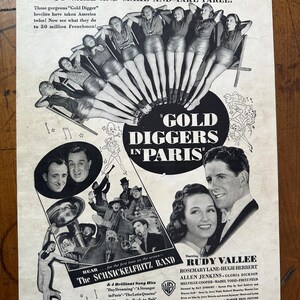 May include: Vintage black and white movie advertisement for "Gold Diggers in Paris." The poster features images of actors, dancers, and text, including the film's title and the names of the stars and the band.