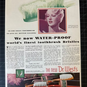 May include: An old advertisement for Dr. West's toothbrushes. The ad shows a woman looking in a mirror, a close-up of a toothbrush, and text highlighting the product's benefits, such as water-proof bristles and improved cleaning.