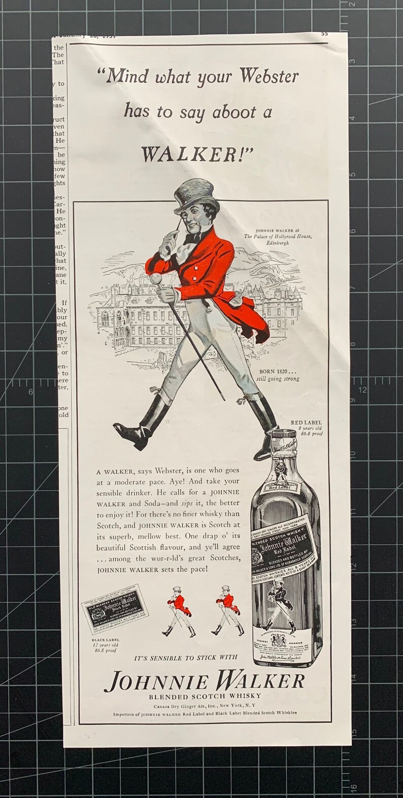 May include: A vintage advertisement for Johnnie Walker blended scotch whisky. The ad features a cartoon illustration of a man in a red coat and top hat walking with a cane. The text reads "Mind what your Webster has to say about a WALKER!" and "It's sensible to stick with Johnnie Walker Blended Scotch Whisky".